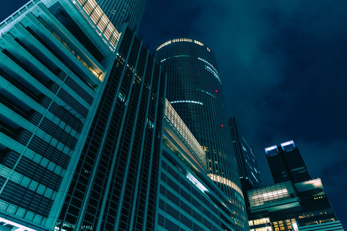 A night view of towering high-rise buildings and modern architecture expressed in cool blue and green tones. It is a cinematic piece that evokes the silence of a sophisticated city and a futuristic sci-fi world.